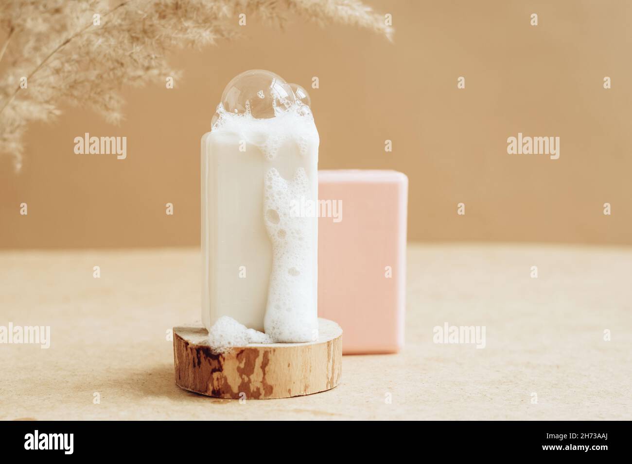 Un morceau de savon naturel bio fait main avec de grandes bulles de mousse sur un podium moderne abstrait. Banque D'Images