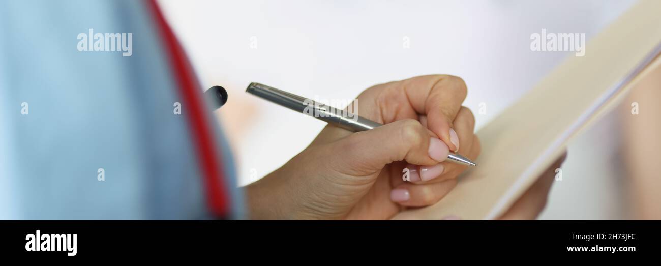 Médecin remplissant les documents médicaux du patient avec un stylo à bille dans la salle de près Banque D'Images