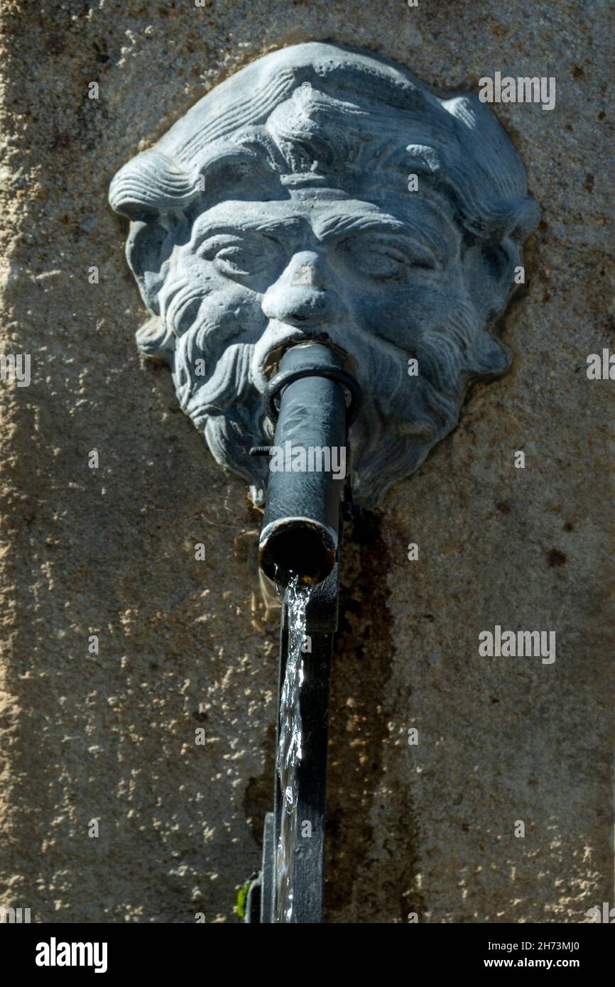 Fontaine décorative en pierre dotée d'un bec verseur à tête de lion placé contre un mur rustique Banque D'Images