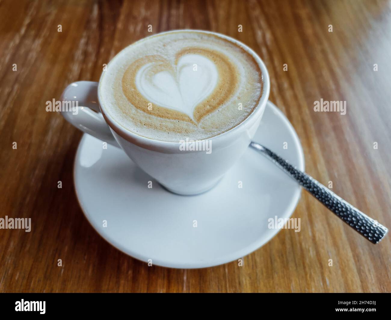 Tasse à café blanche avec latte en forme de cœur dans un café. Banque D'Images