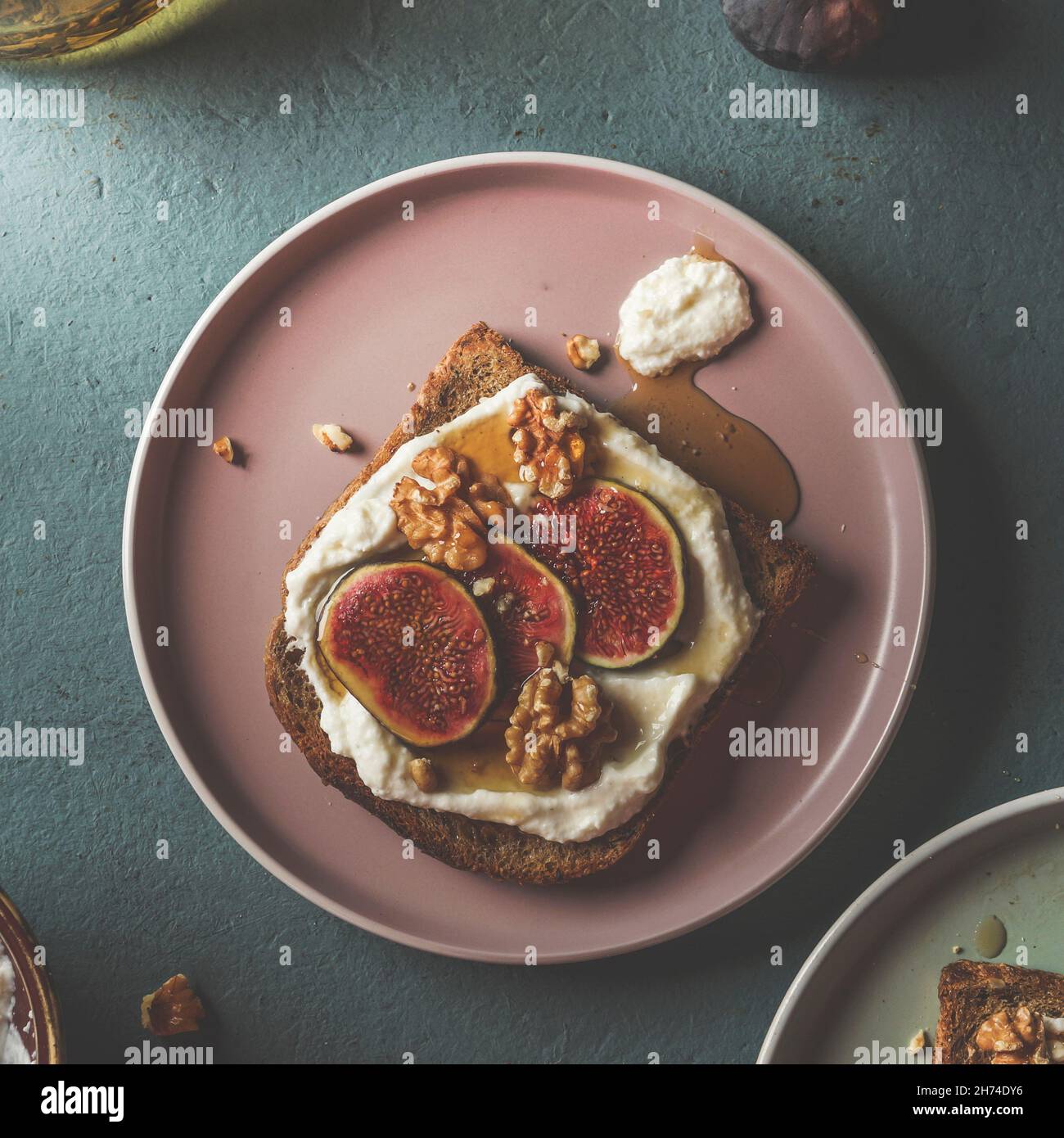 Toast français avec fromage à la crème, figues et sirop d'érable sur une assiette rose pâle à la table de cuisine bleue.Idée de petit déjeuner végétarien sain.Vue de dessus. Banque D'Images