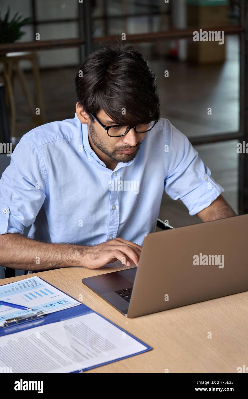 Jeune homme d'affaires indien de l'est utilisant un ordinateur portable travaillant au bureau. Banque D'Images