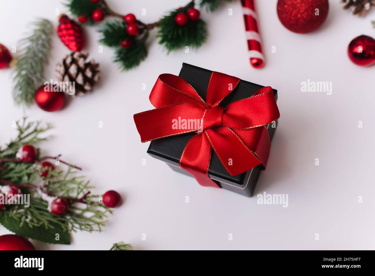 Composition du nouvel an ou de Noël sur fond blanc avec boîte cadeau, ruban rouge avec branches de sapin, jouets, espace de copie pour Félicitations. Banque D'Images
