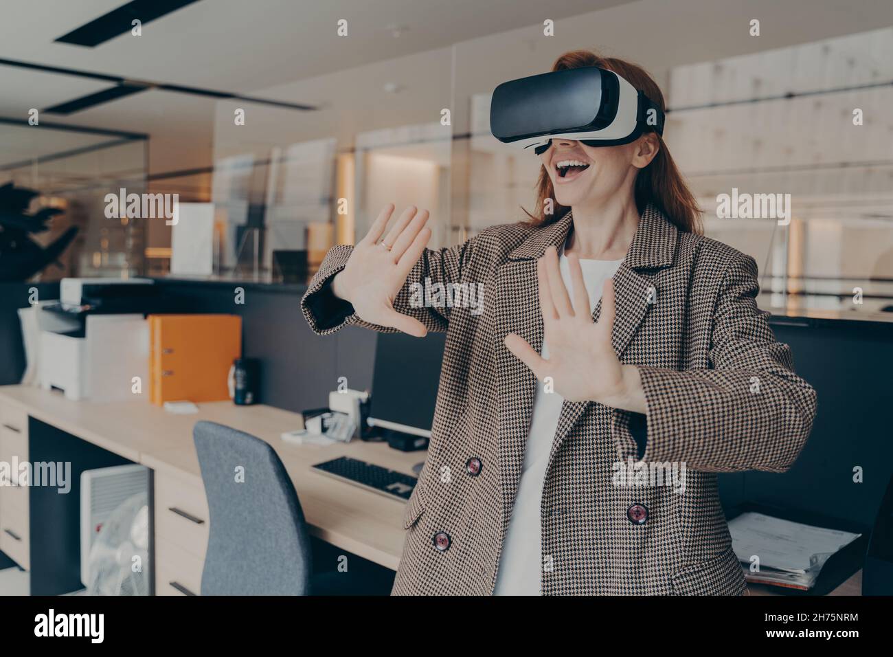 Femme portant un casque VR s'amusant dans un jeu de réalité virtuelle au bureau Banque D'Images