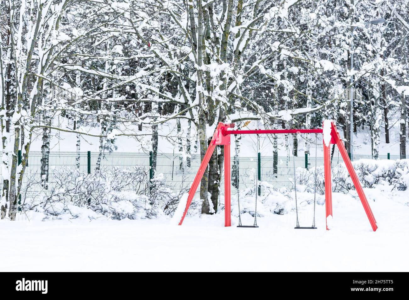 balançoires rouges dans une aire de jeux pour enfants lors d'une journée d'hiver enneigée Banque D'Images