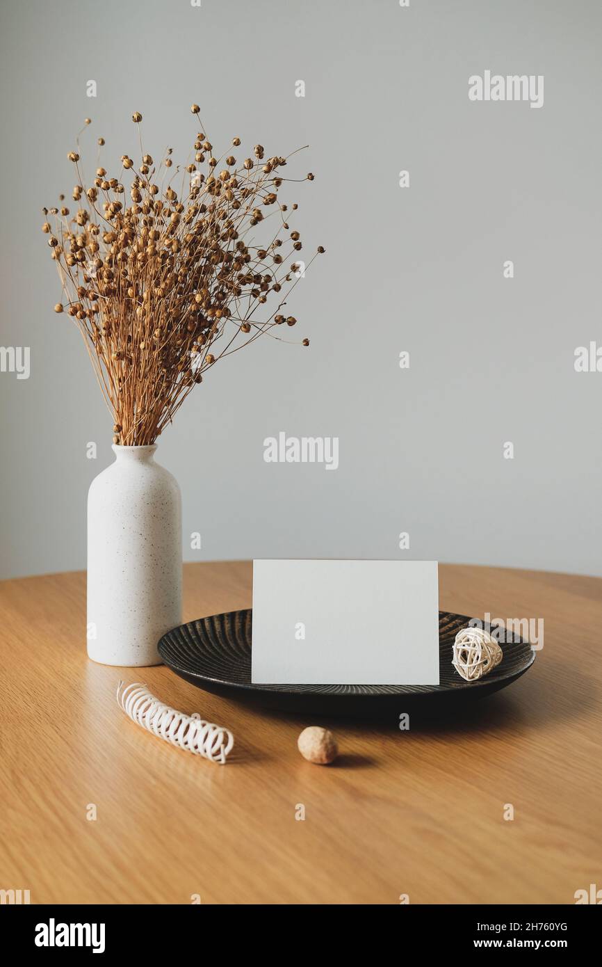 Maquette papier vierge sur plaque et vase de lin sec sur table en bois.Intérieur du café.Style nordique. Banque D'Images