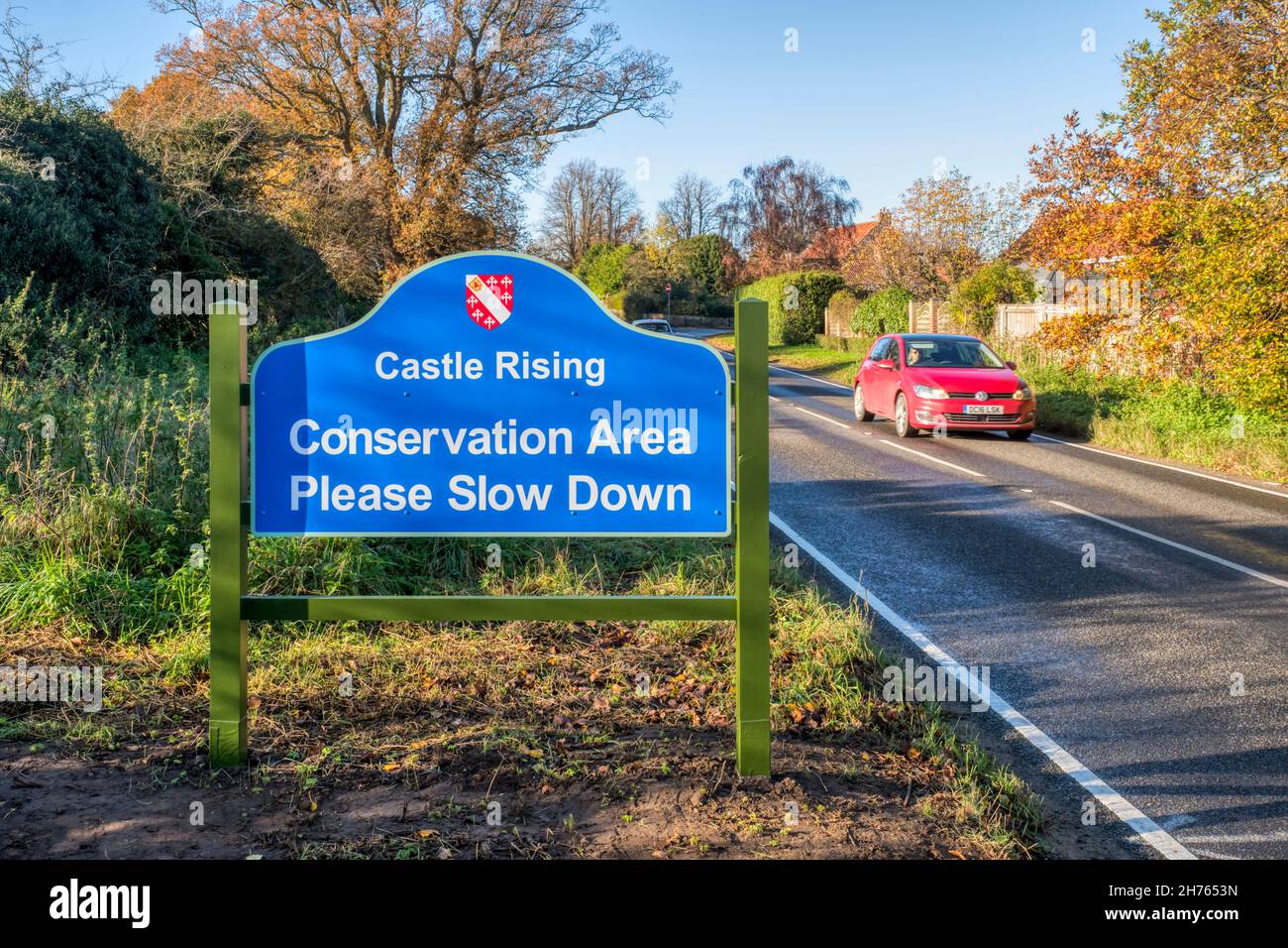 Voitures passant le panneau lecture zone de conservation Veuillez ralentir à l'entrée du village de Castle Rising à Norfolk. Banque D'Images