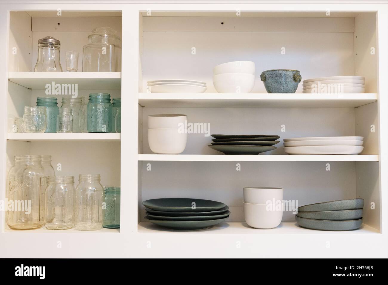 Armoires de cuisine avec un concept ouvert (pas de portes) contenant des pots et des plats de maçon clairs, blancs et de couleur aqua. Banque D'Images