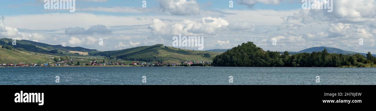 Le village de Parnaya est situé sur la rive du Big Lake, sur le fond des collines forestières, un jour d'été.Région de Krasnoyarsk.Russie. Banque D'Images