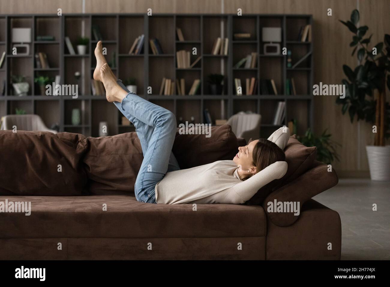 Femme insouciante couchée sur un canapé avec les jambes relevées Banque D'Images