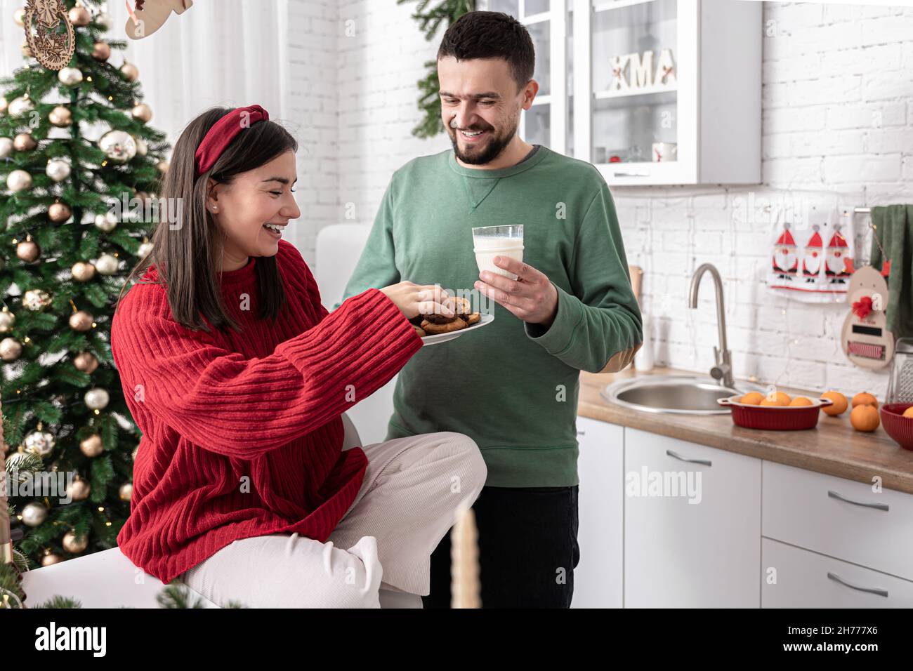 Un mari et une femme heureux avec des biscuits de Noël et du lait dans la cuisine. Banque D'Images