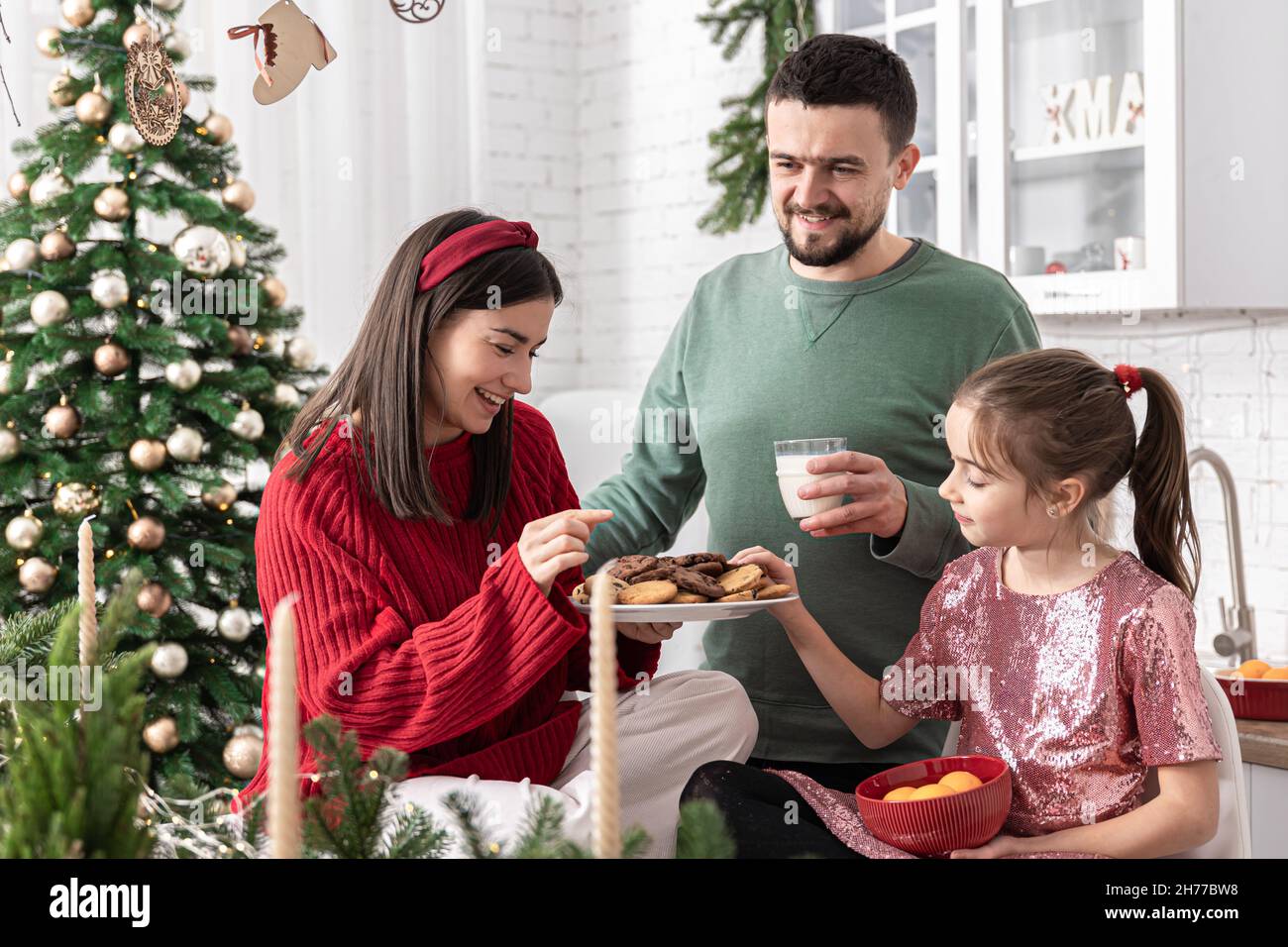 Bonne famille avec des biscuits de Noël et du lait dans la cuisine. Banque D'Images
