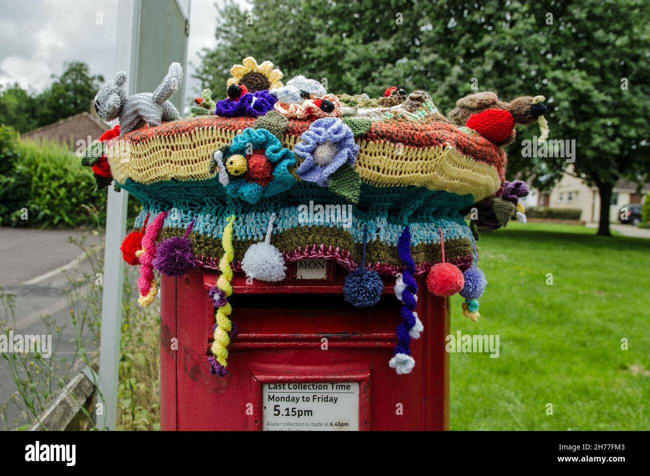 Basingstoke, Royaume-Uni - 4 juillet 2021 : dessus d'une boîte pilier de poste avec décoration en fil de bombardement d'un chapeau crochetté avec animaux, fleurs et pompons Banque D'Images