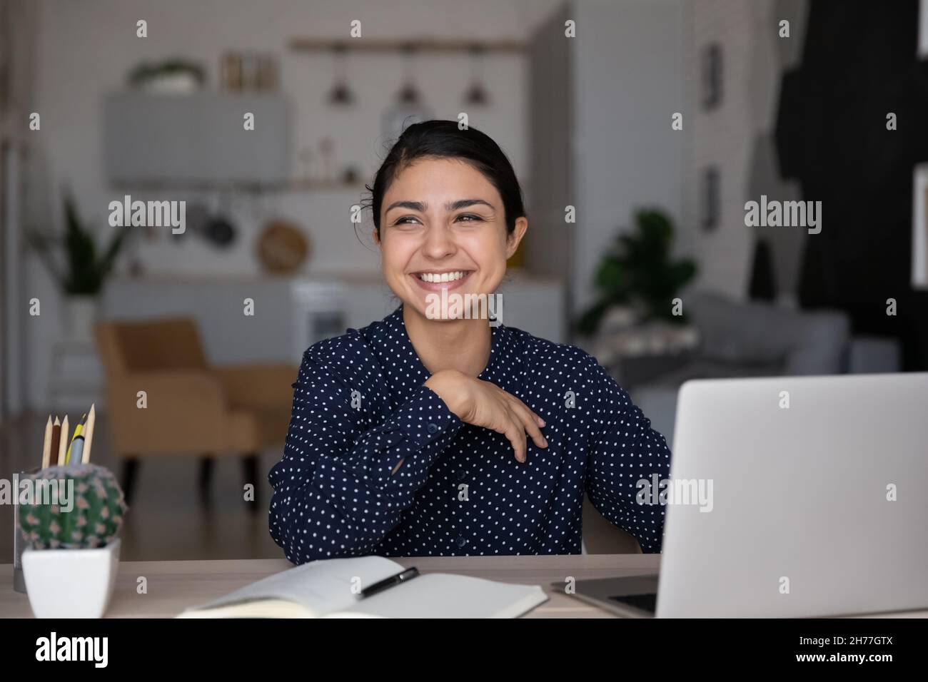 Jeune femme indienne souriante et rêveuse à distance. Banque D'Images