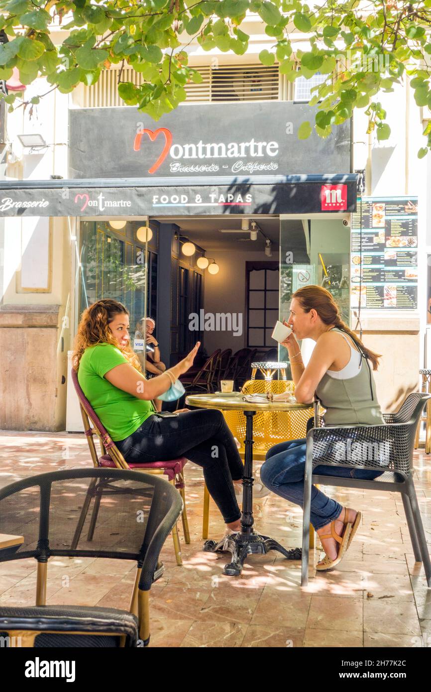 Deux jeunes femmes s'asseyant dans un café sur le trottoir buvant un café devant un bar à tapas dans la ville espagnole de Valence en Espagne Banque D'Images