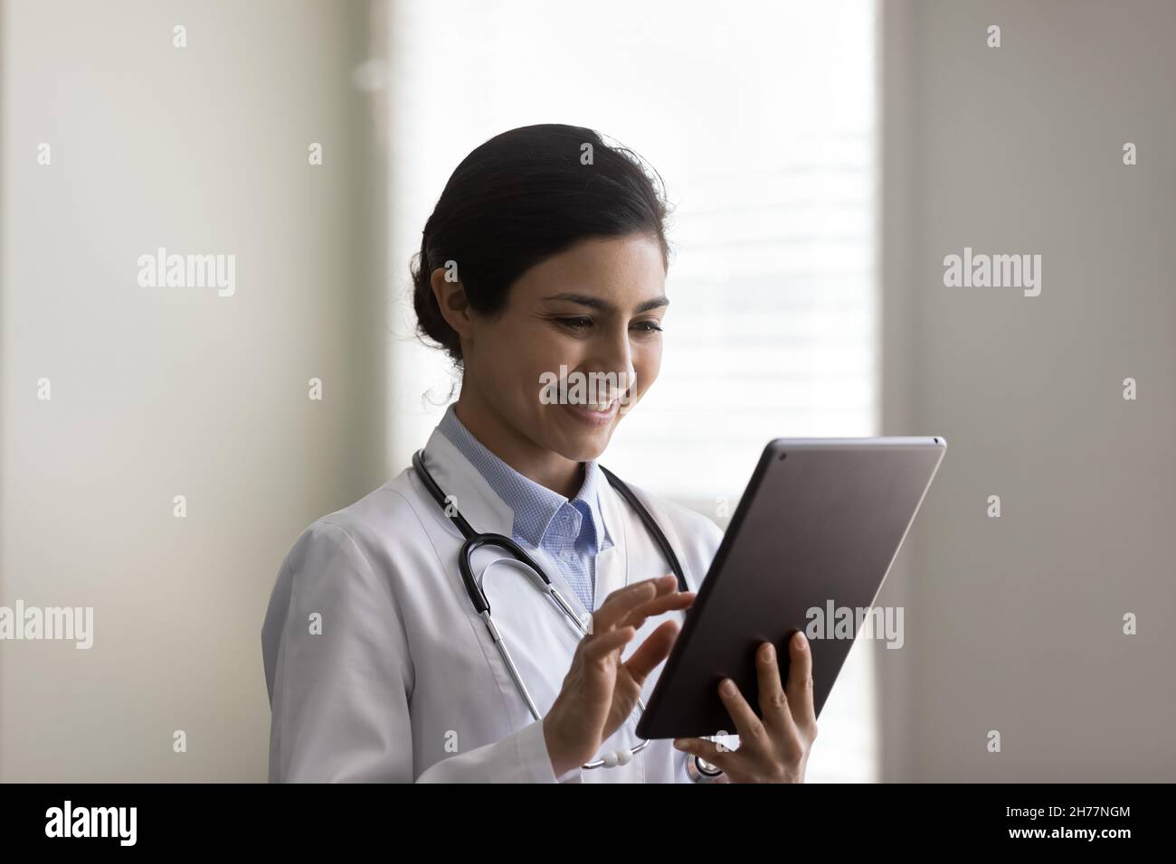 Coup de tête souriant jeune femme indienne médecin utilisant une tablette Banque D'Images