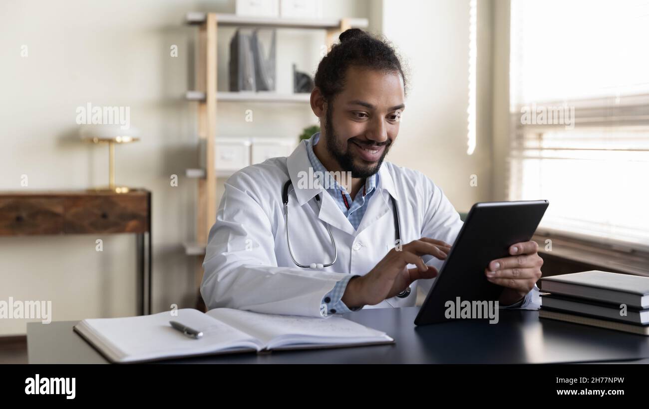 Sourire Afro-américain homme médecin utilisant une tablette dans le bureau Banque D'Images
