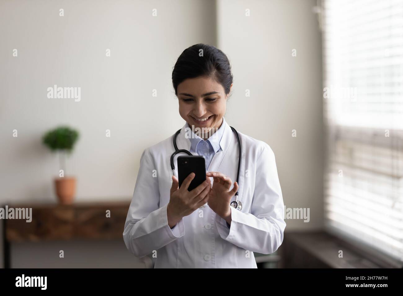 Coup de tête souriant femme indienne médecin médecin à l'aide d'un smartphone Banque D'Images