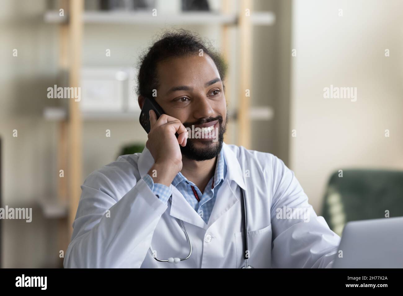 Coup de tête souriant homme afro-américain médecin parlant au téléphone Banque D'Images