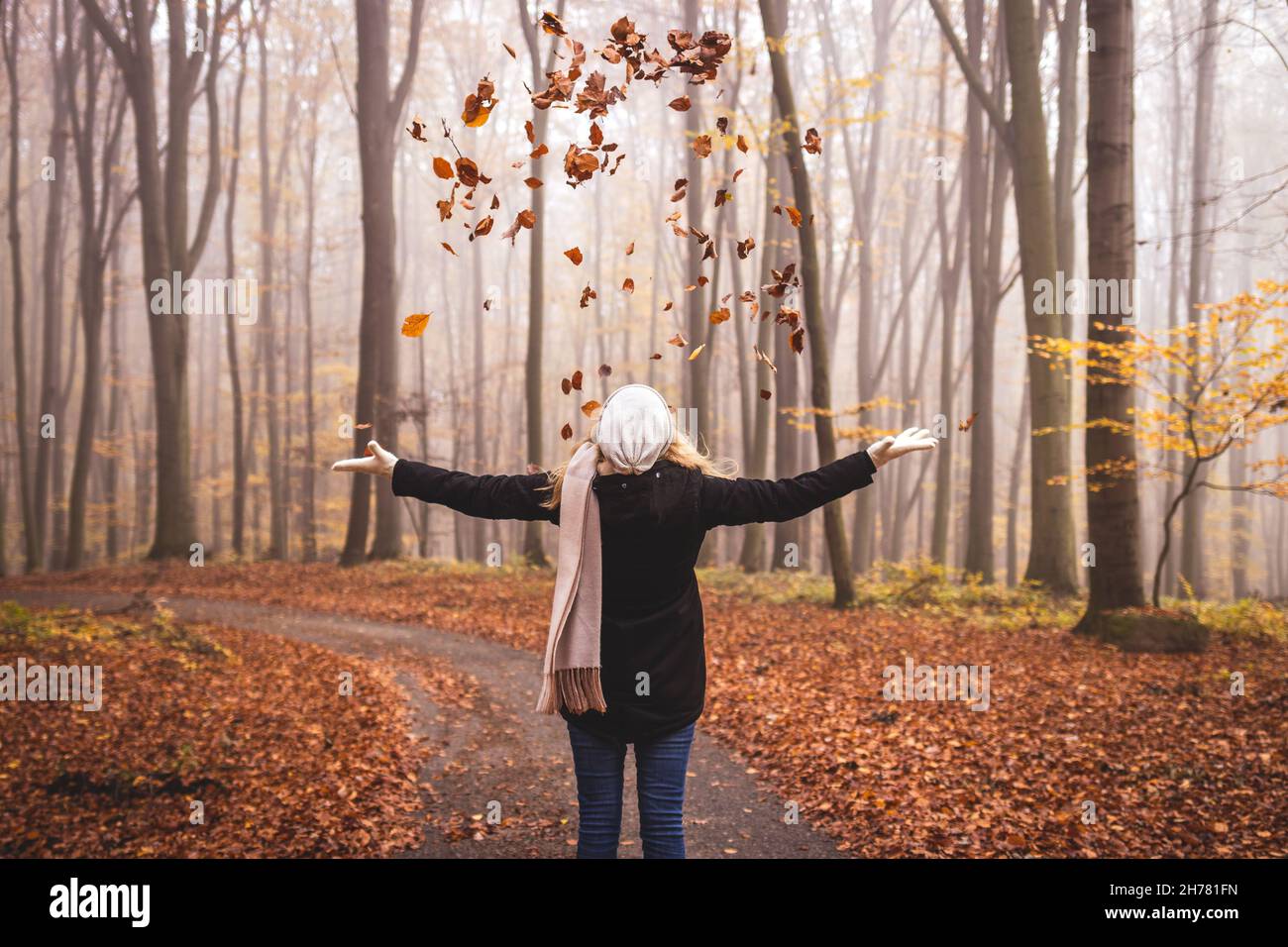 Une femme heureuse jette des feuilles d'automne dans les airs.Profitez de la randonnée dans les bois à l'automne Banque D'Images