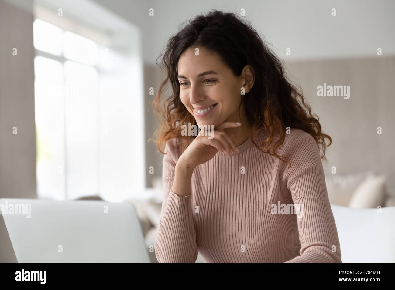 Une femme d'affaires souriante regarde l'écran d'un ordinateur portable, travaille en ligne Banque D'Images