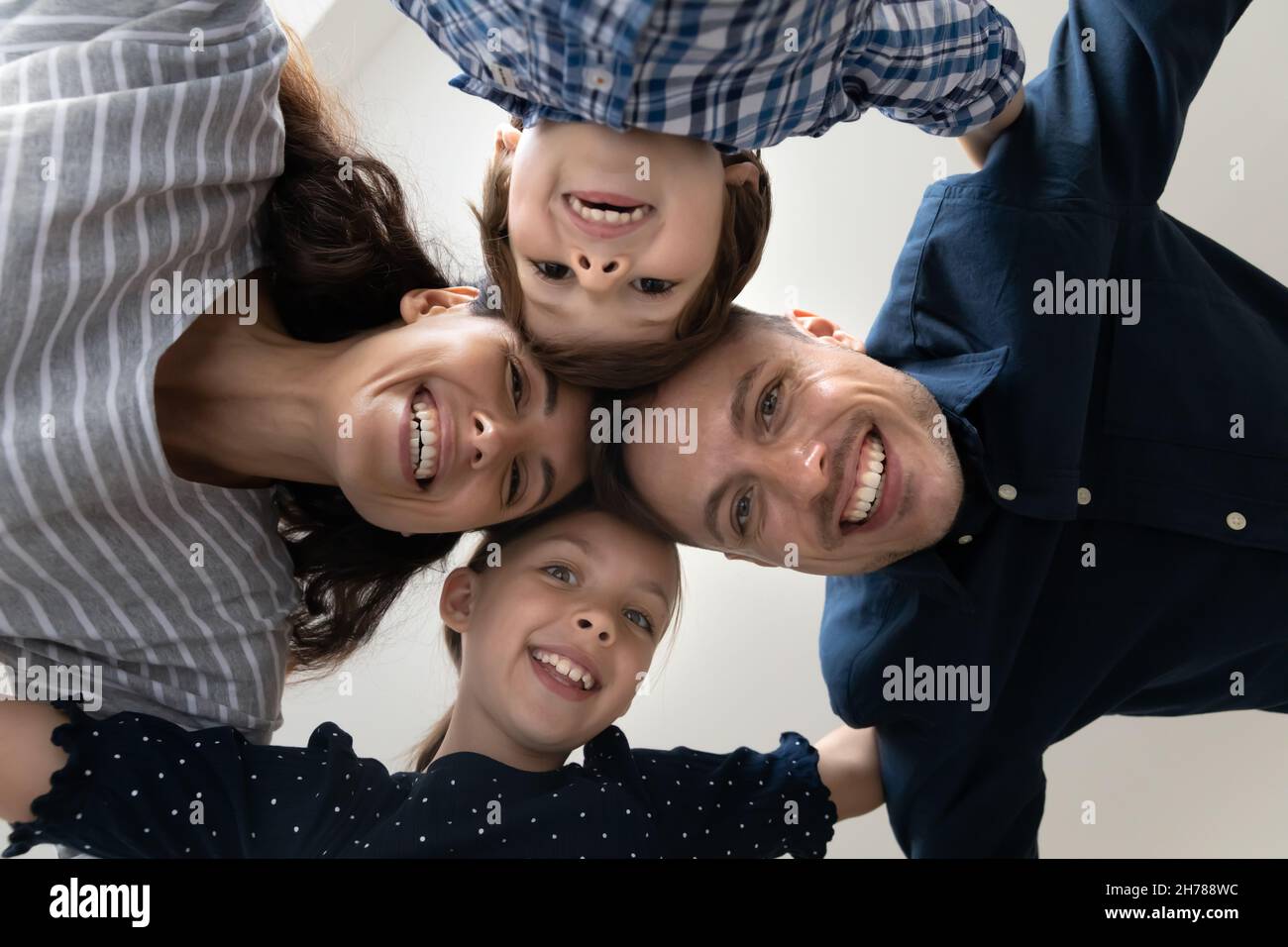 La vue de dessous fait face à la famille avec les enfants souriant en regardant l'appareil photo Banque D'Images