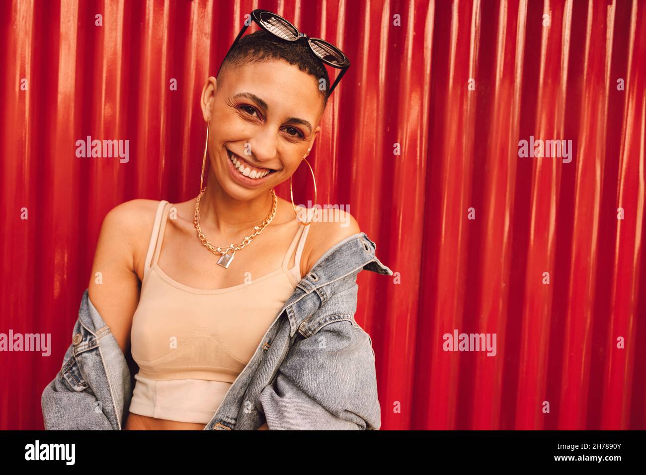 Jolie jeune femme souriant à la caméra tout en se tenant seule sur un fond rouge.Une jeune femme insouciante se sente vibrante et pleine de vie. Banque D'Images