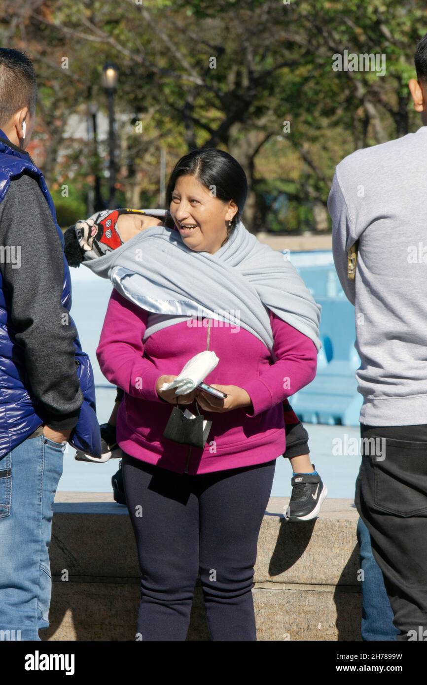 Une grand-mère tenant un enfant dans un rebozo, un châle mexicain traditionnel pour tenir des enfants.Dans un parc à Queens, New York. Banque D'Images