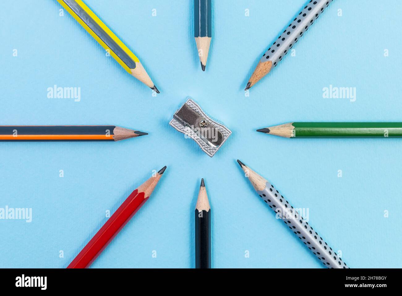 Taille-crayons en métal avec huit crayons graphite différents sur fond bleu Banque D'Images