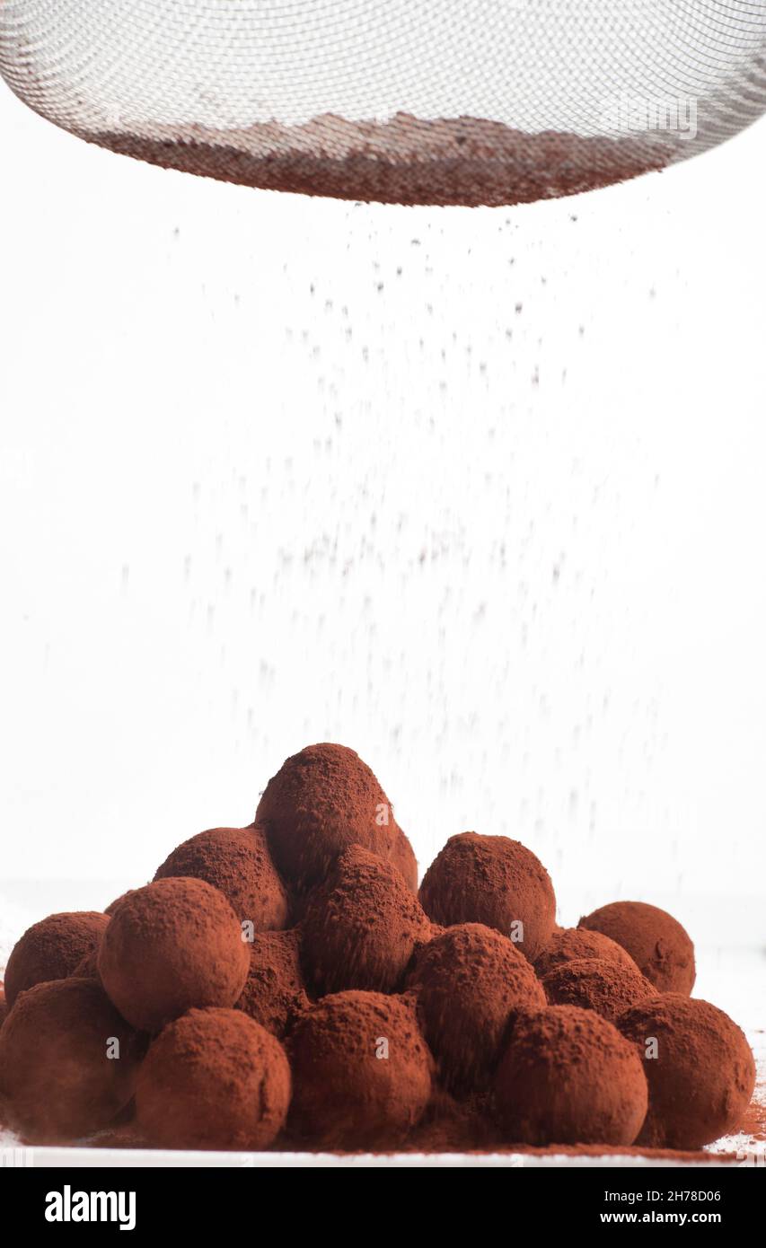 Les truffes au chocolat sur fond blanc cacao en poudre est dispersée avec une passoire Banque D'Images