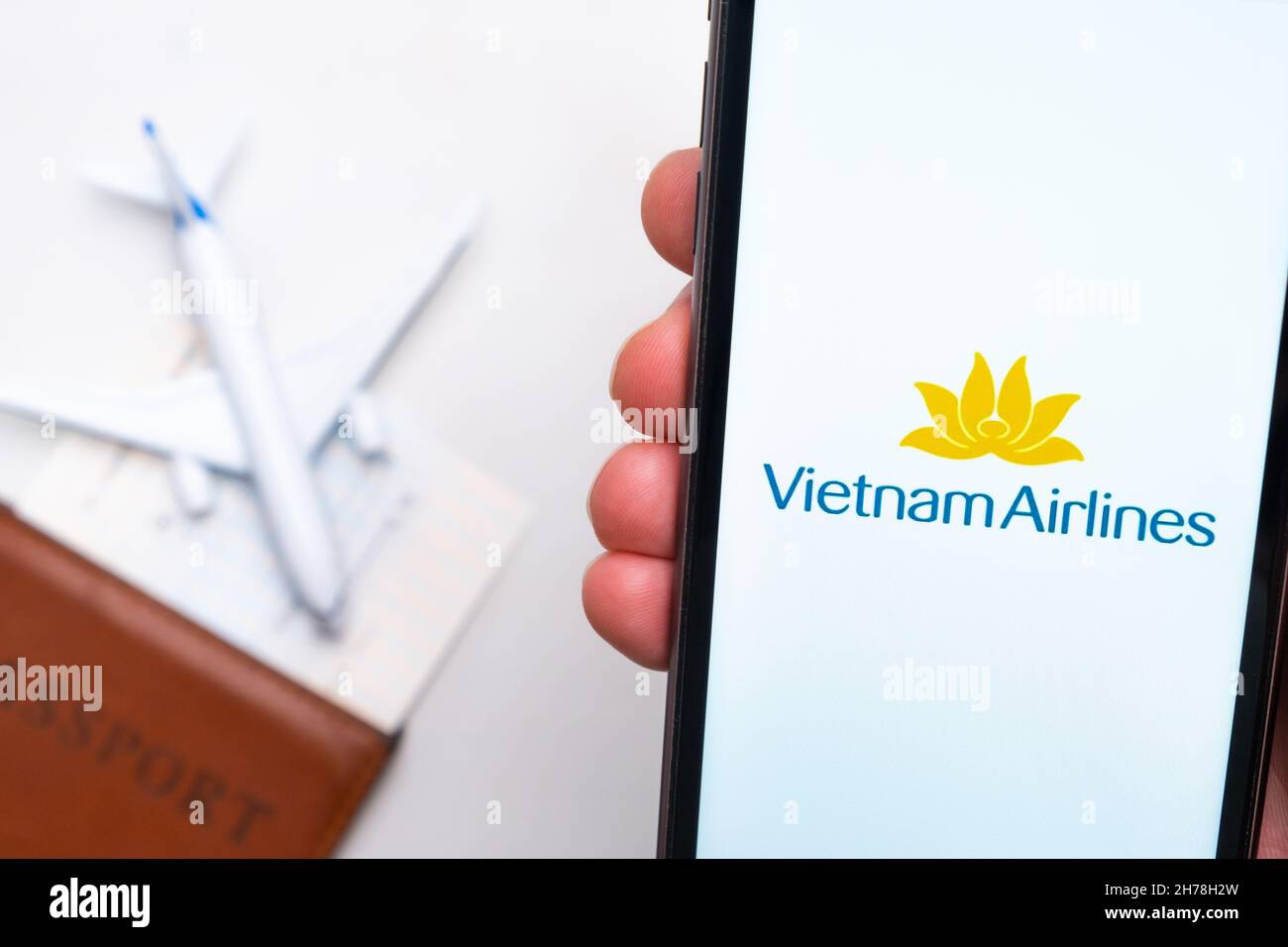 L'application VietnamAirlines sur l'écran d'un smartphone dans la main de man.Un avion jouet, un passeport et des billets sont sur la table.Novembre 2021, San Francisco, États-Unis Banque D'Images