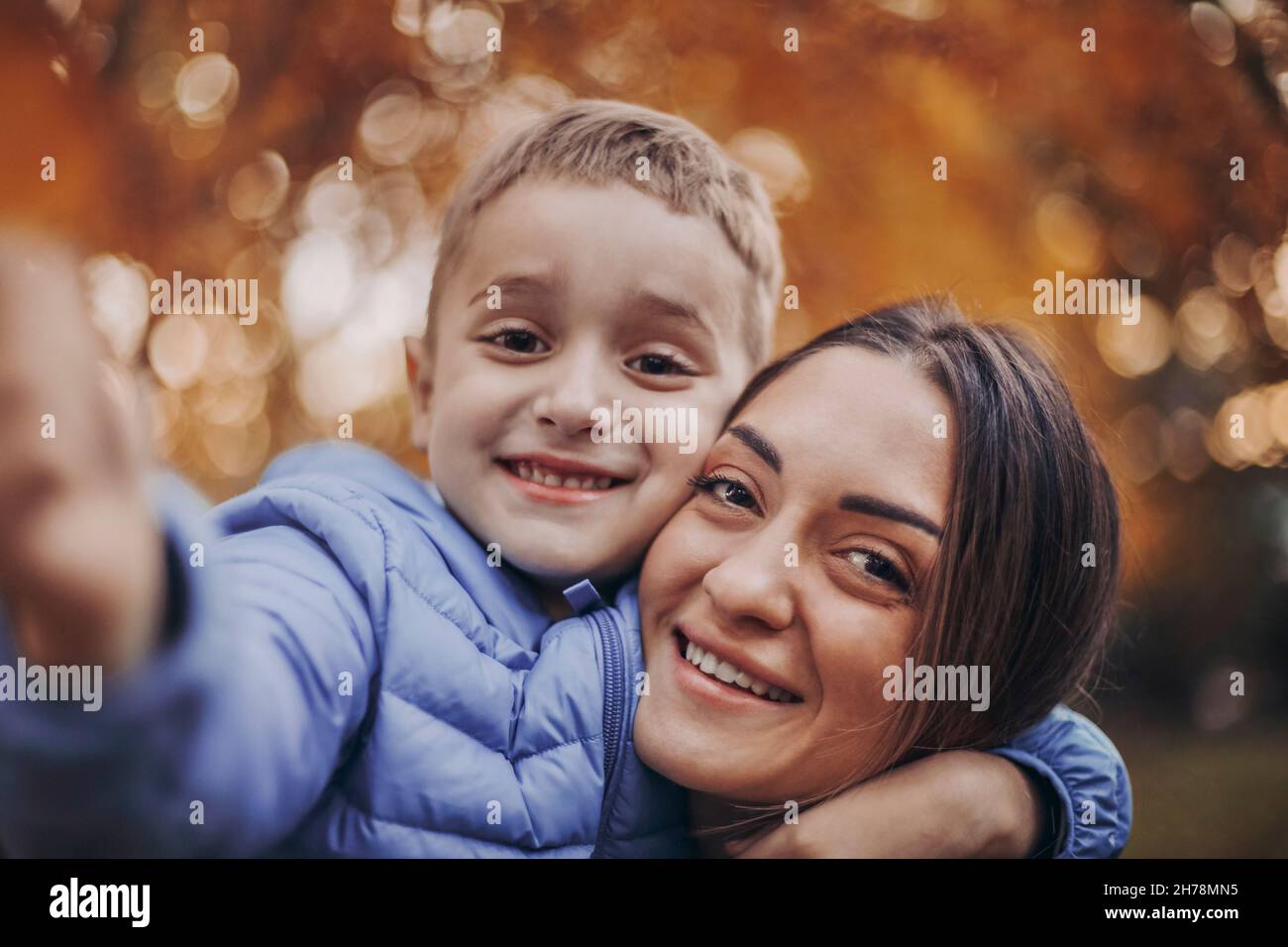 Jeune famille heureuse, mère et petit fils enfant marchant dans la forêt d'automne, enfant tenant la feuille d'arbre jaune à la main tout en passant du temps avec maman dans la belle Banque D'Images