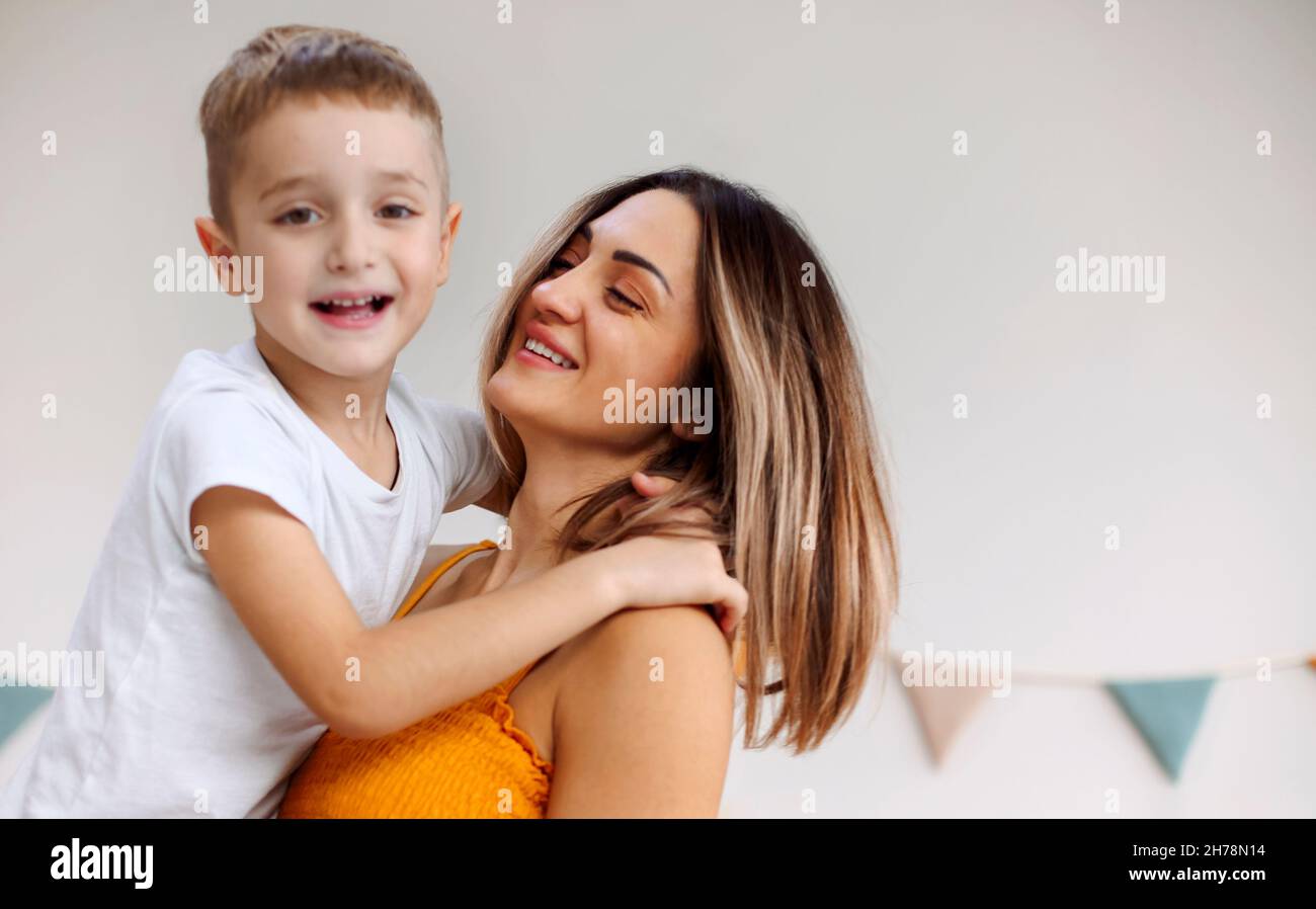 Jeune famille heureuse mère aimante et son enfant fils s'amuser ensemble à la maison, jouer et rire.Enfant souriant embrassant sa mère, heureux de Banque D'Images