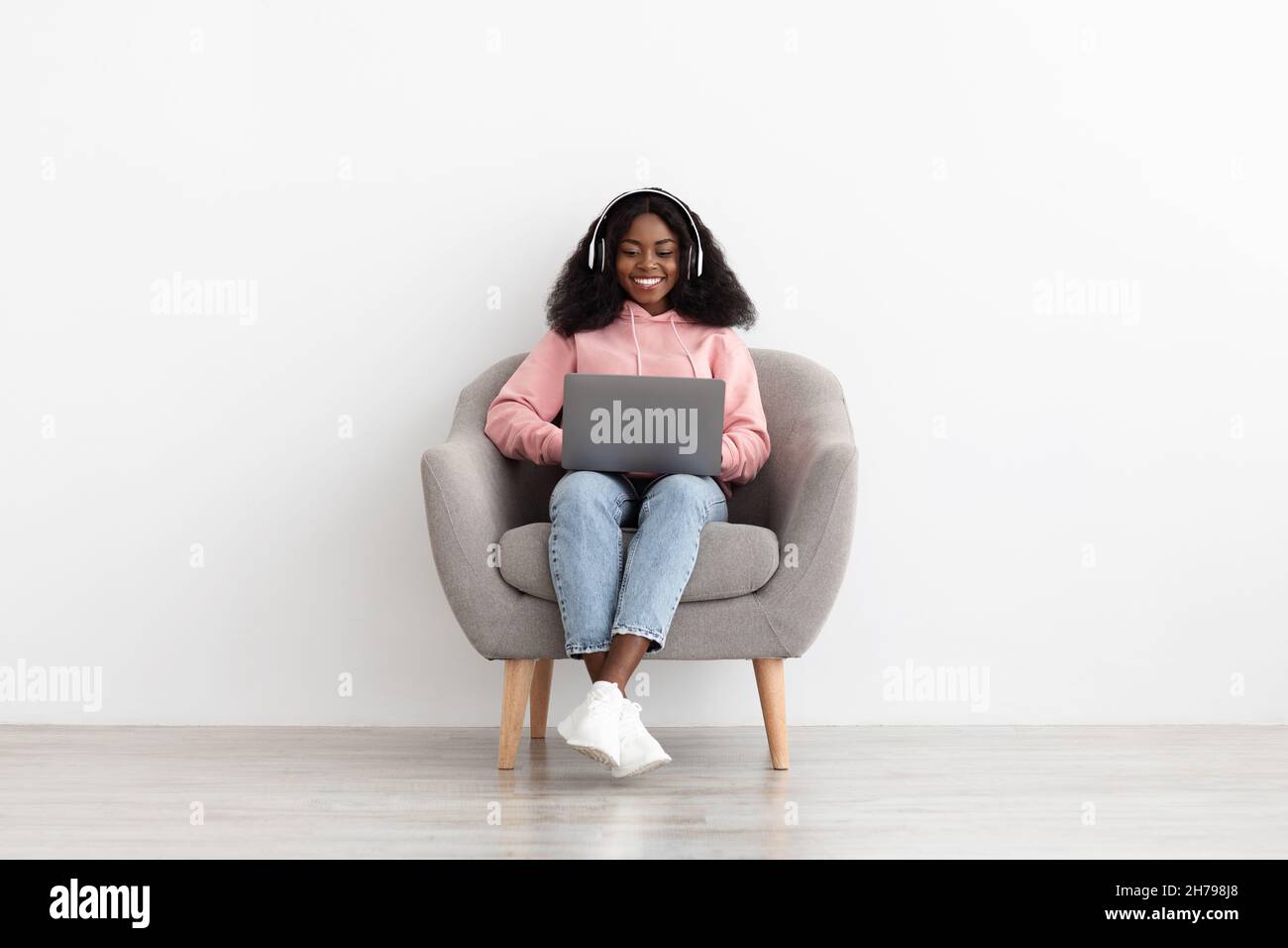 Femme afro-américaine souriante regardant un film en ligne, sur un ordinateur portable Banque D'Images
