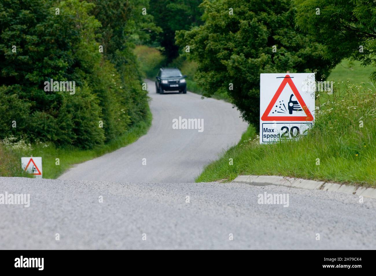Une voiture de tourisme approche d'un panneau de vitesse maximale de 20 mph sur une route de pays B couverte de copeaux de pierre frais, Leicestershire, Angleterre, Royaume-Uni. Banque D'Images