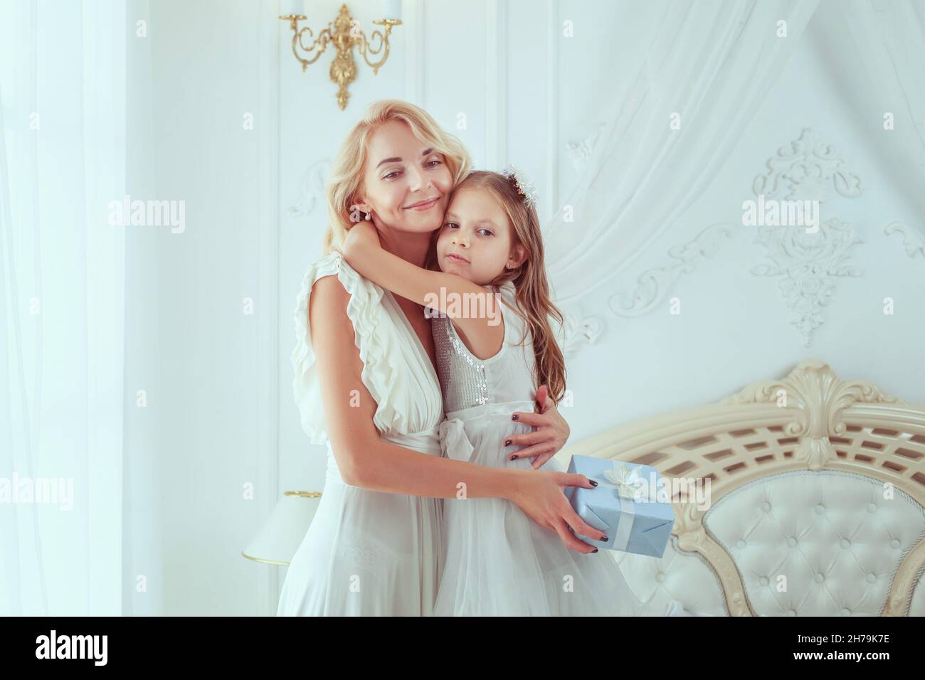 Fille a donné à sa mère un cadeau de Noël.Ils embrassent. Banque D'Images