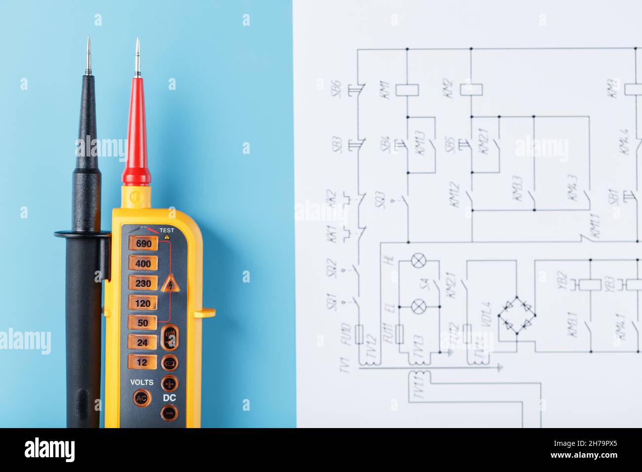 Indicateur de tension jaune avec un schéma électrique sur fond bleu.Test et vérification des réseaux électriques Banque D'Images