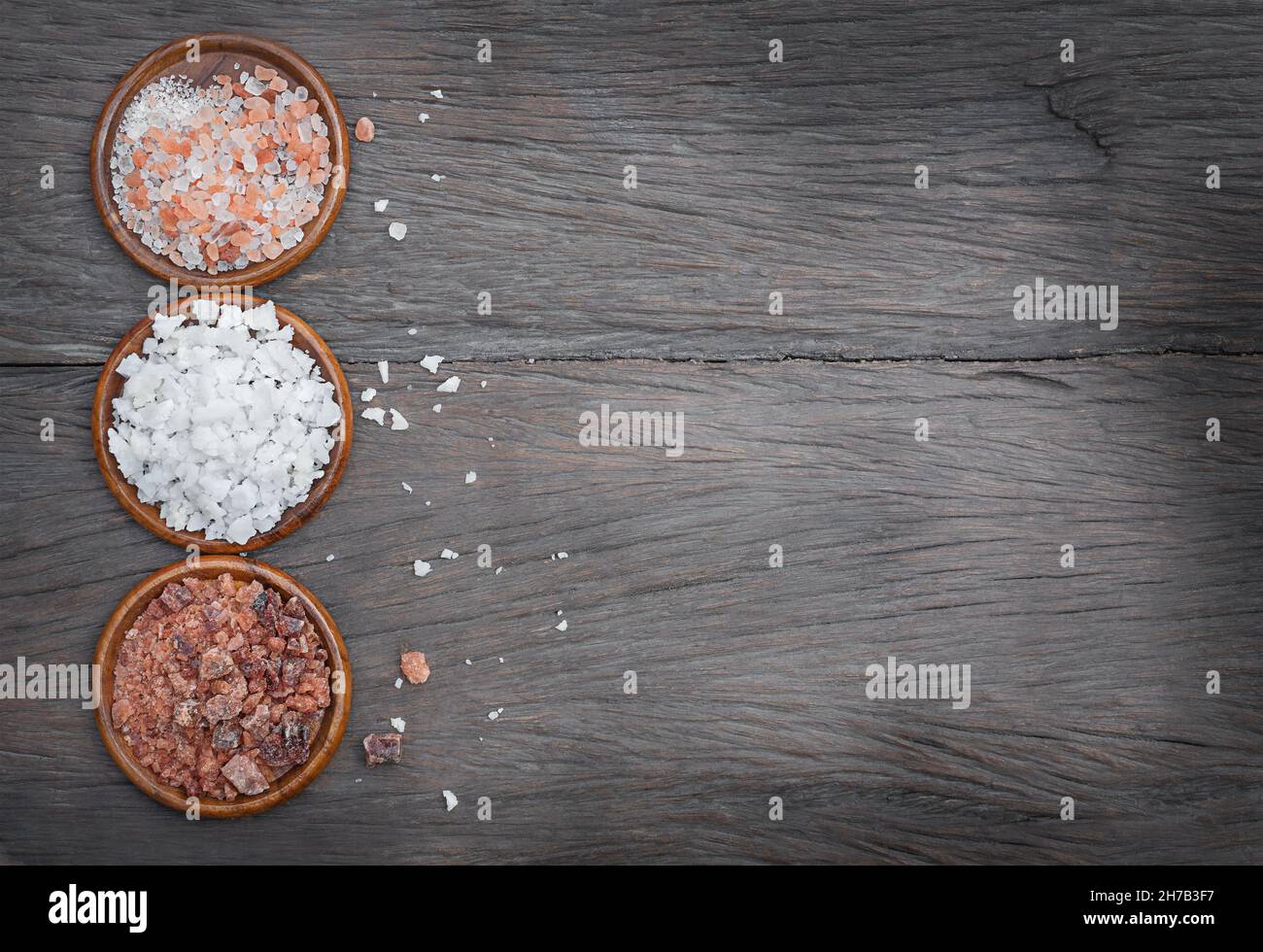 Trois sortes de sel dans des bols en bois sur fond de bois Banque D'Images