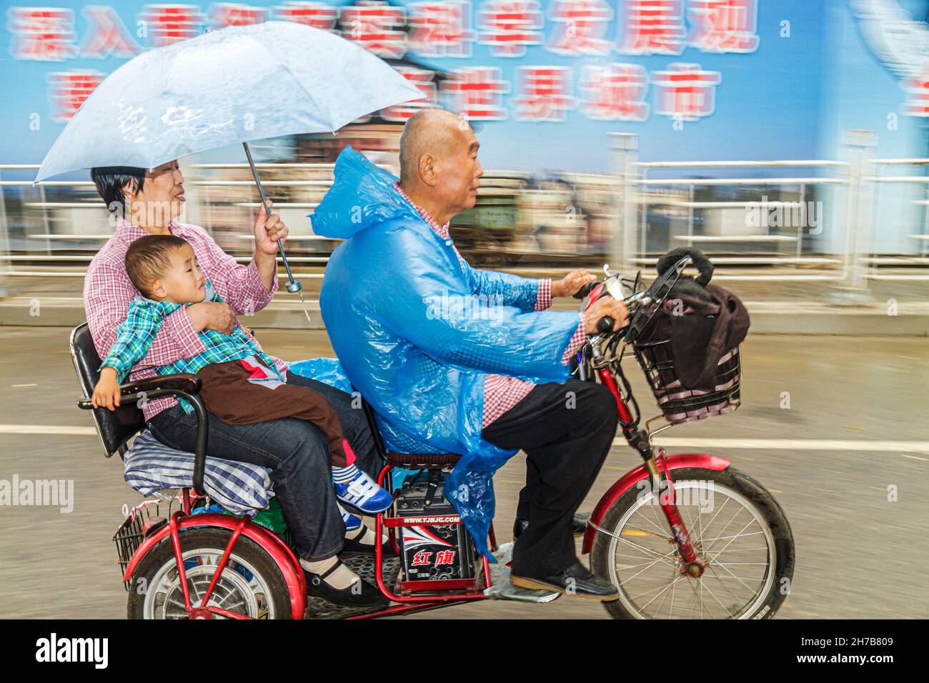Beijing Chine, Guanganmen Outer Street, tricycle cyclé électrique, homme asiatique femme mâle, grand-parents garçon petit-fils parapluie équitation pluie Banque D'Images