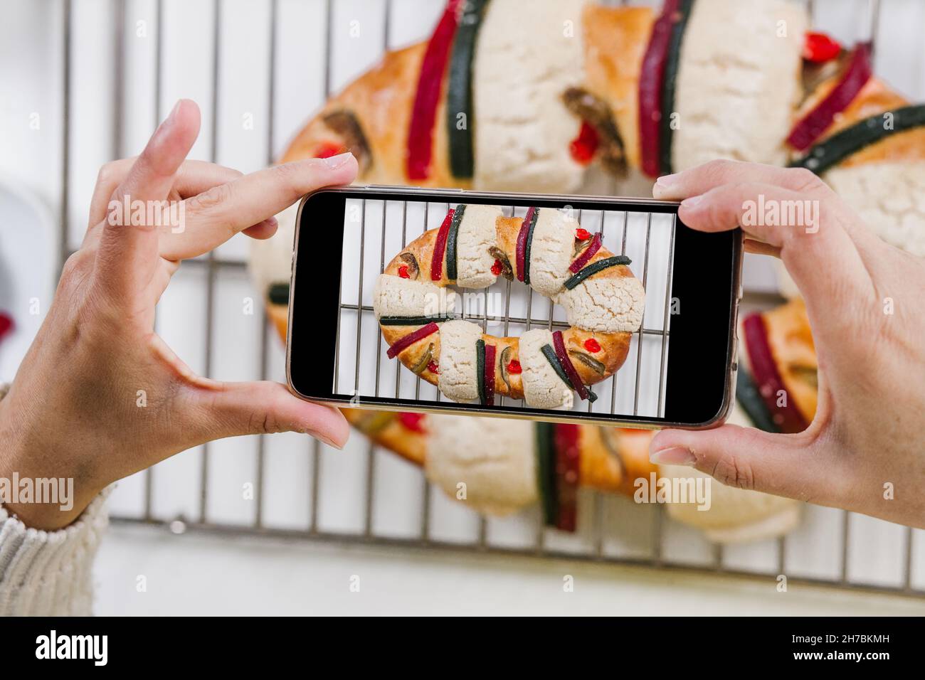 Femme mexicaine cuisant un traditionnel rosca de reyes ou épiphanie gâteau et prenant des photos avec téléphone mobile dans la cuisine à la maison pour Kings Day au Mexique Latin Banque D'Images