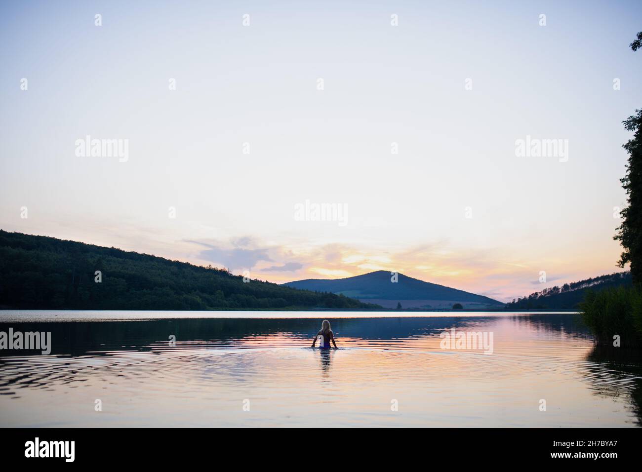 Vue arrière de la femme active nageuse plongée en plein air dans le lac, scène panoramique avec coucher de soleil Banque D'Images