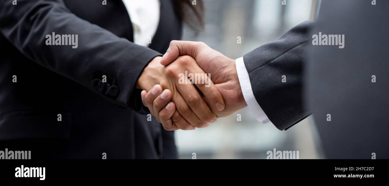 Femme d'affaires en tenue officielle faisant poignée de main avec partenaire d'affaires à l'extérieur dans la ville, bannière panoramique proportion Banque D'Images