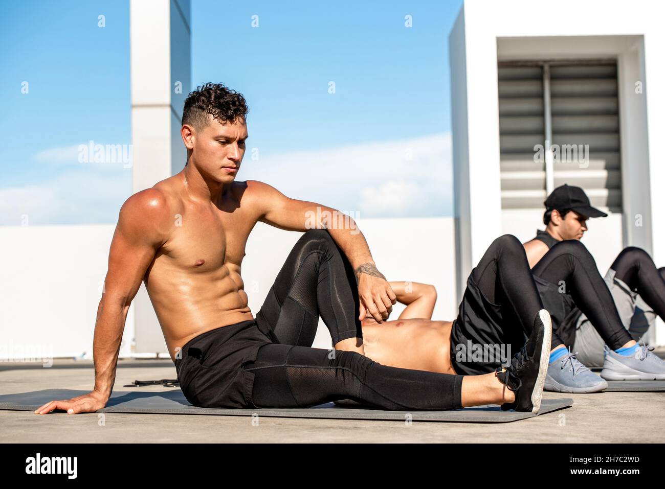 Diversity FIT masculin groupe de bodybuilder faire de l'exercice de poids corporel à l'extérieur sur le toit du bâtiment Banque D'Images