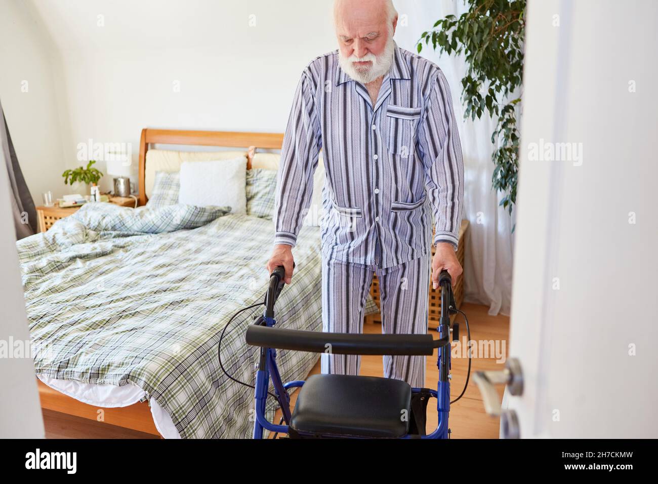 Senior en pyjama apprend à marcher après un accident vasculaire cérébral avec le rotateur dans la clinique de réadaptation Banque D'Images