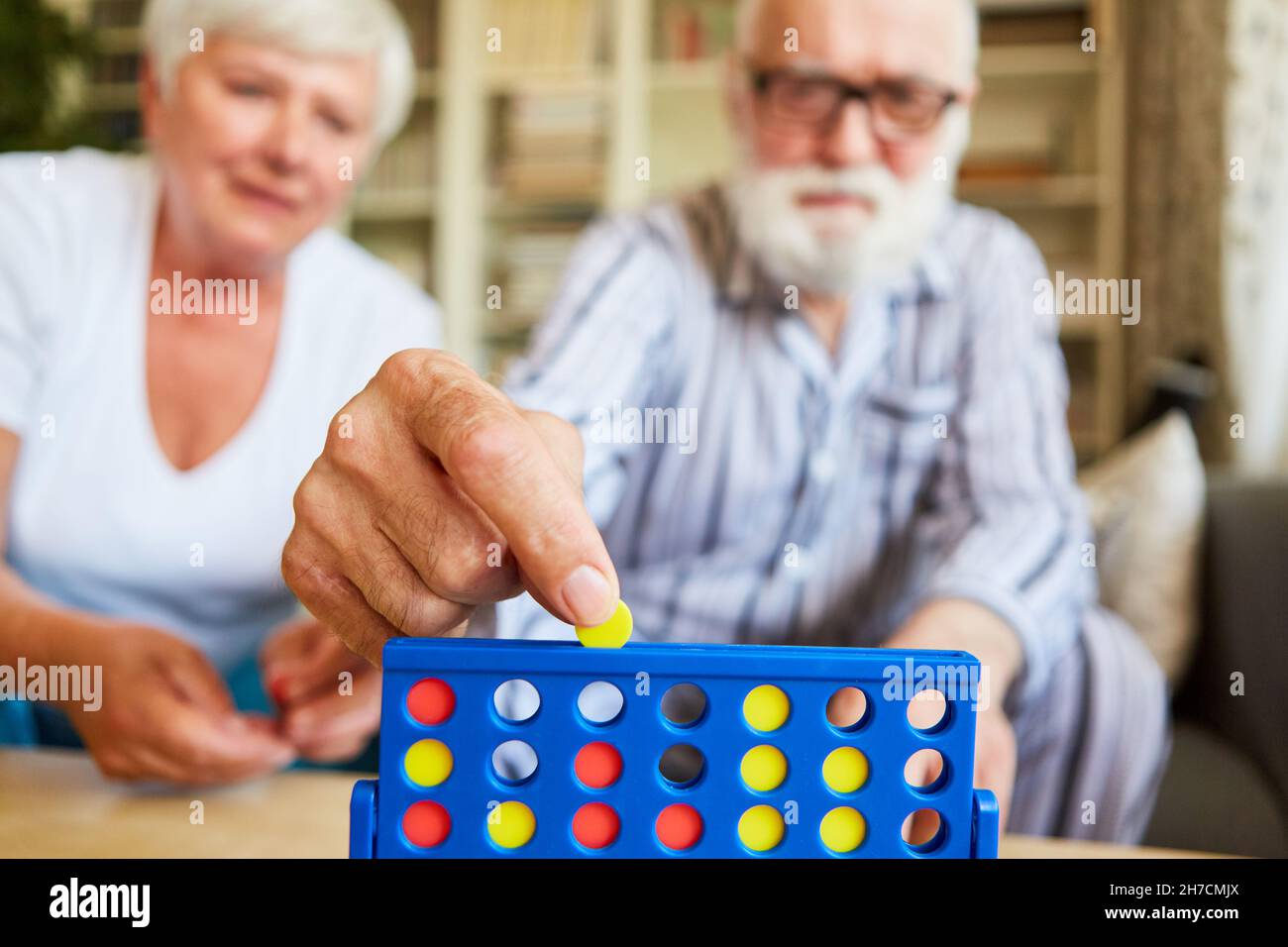 Les aînés jouent le jeu de stratégie quatre victoires à la maison comme un cerveau teaser et le jogging de cerveau Banque D'Images