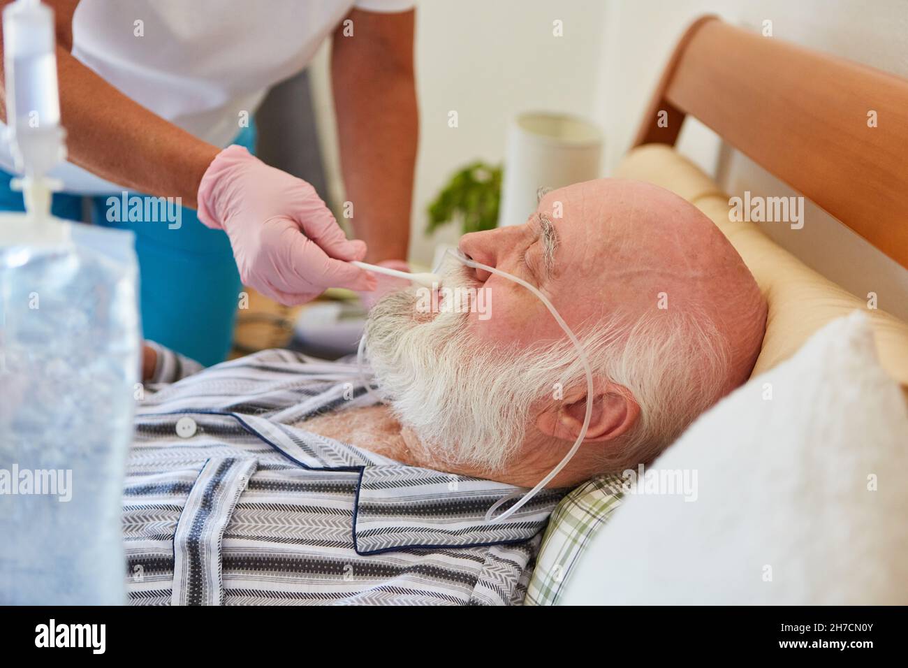 Une infirmière a humidifié les lèvres du patient avec des lunettes d'oxygène dans le lit d'hôpital Banque D'Images