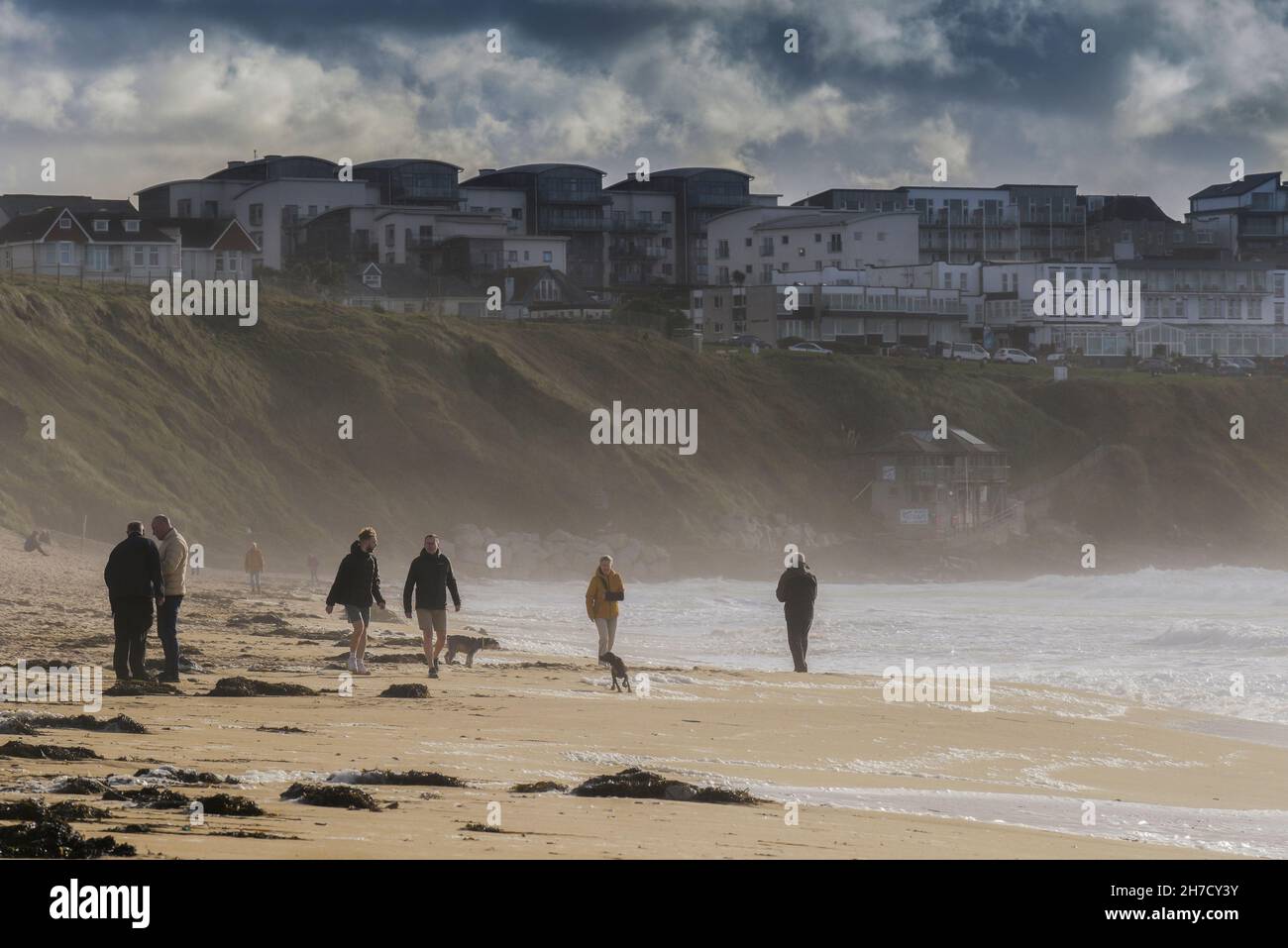 Les gens qui profitent d'une marche énergique sur la plage par temps venteux à Fistral à Newquay en Cornouailles. Banque D'Images