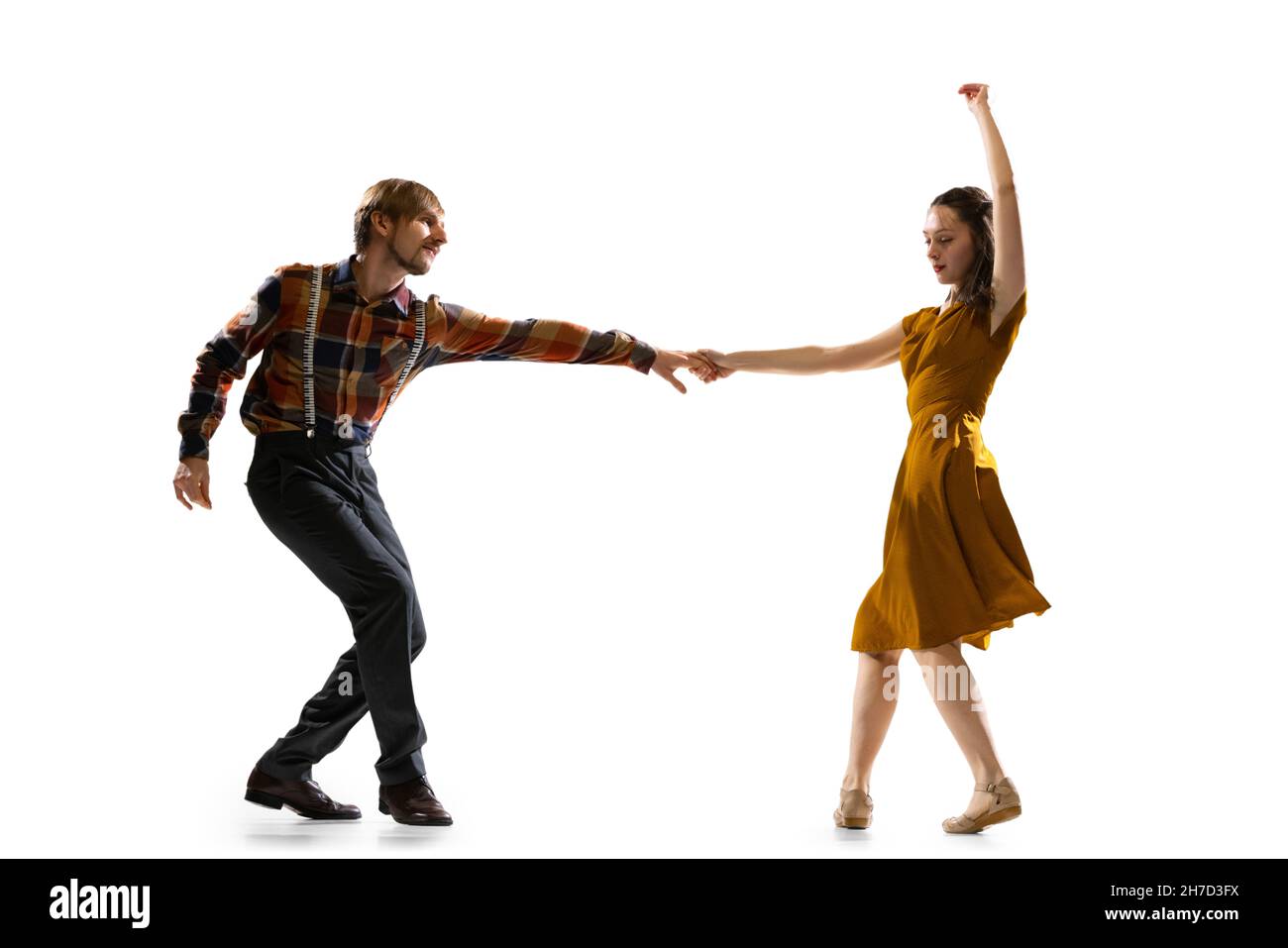 Portrait dynamique de danseurs élégants, jeune homme et femme en tenue vintage dansant balançoire isolée sur fond blanc Banque D'Images