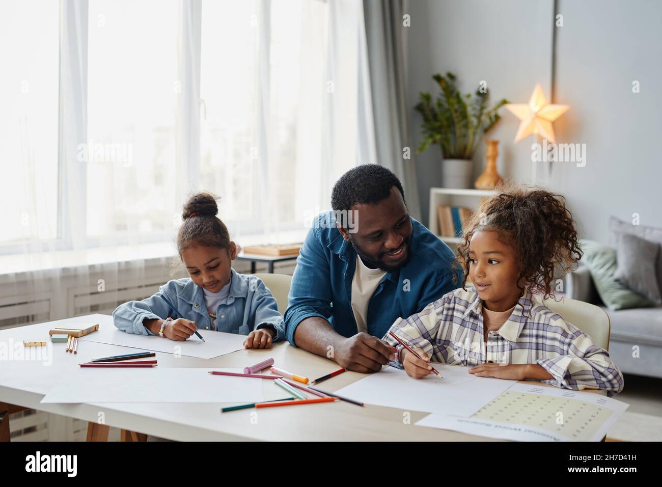 Portrait d'un père afro-américain aimant avec deux filles qui dessinant ensemble dans une maison confortable, espace de copie Banque D'Images