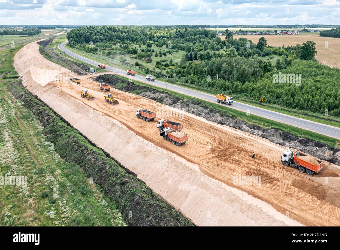 vue panoramique aérienne d'un grand chantier de construction de routes avec des machines lourdes - bulldozer, niveleuse, terrassement et camions à benne basculante Banque D'Images